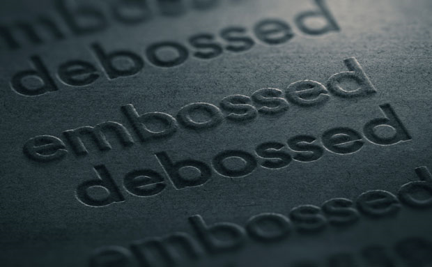 The words embossed and debossed pressed into a dark substrate