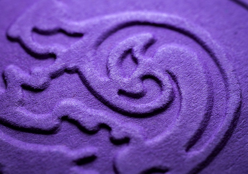 A swirly design embossed on a purple substrate