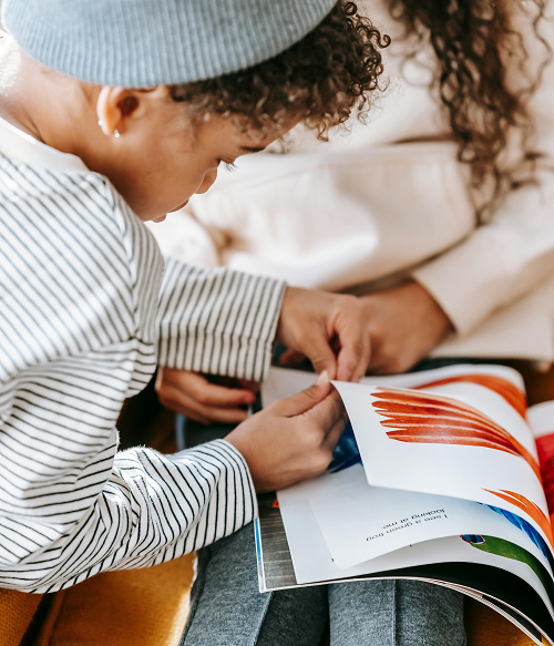 A young boy turning the pages of a softcover children's book</i>