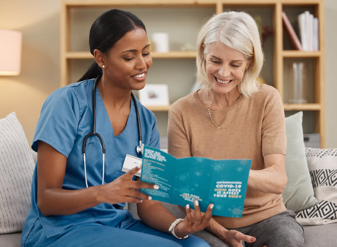 A female nurse and a female patient look at a Covid pamphlet