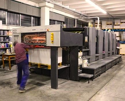 A man loading paper into a sheet fed Offset printing press