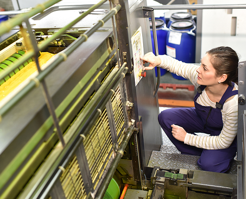 A female press operator preparing to adjust settings on an offset  printing pressate 