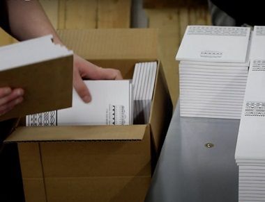 A printing plant worker packs a box with logo notepads