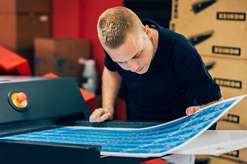 A man looking over a large printed sheet