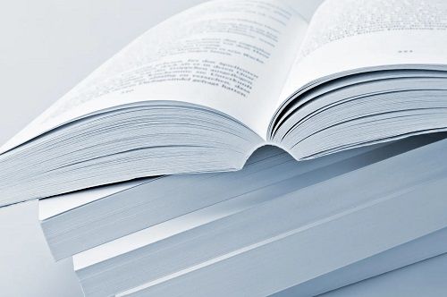 An open book lying on top of a stack of closed books