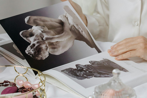 A person looking through an art book of sculptures