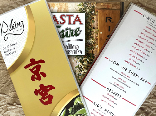 Three laminated restaurant menus lying on a gold tablecloth