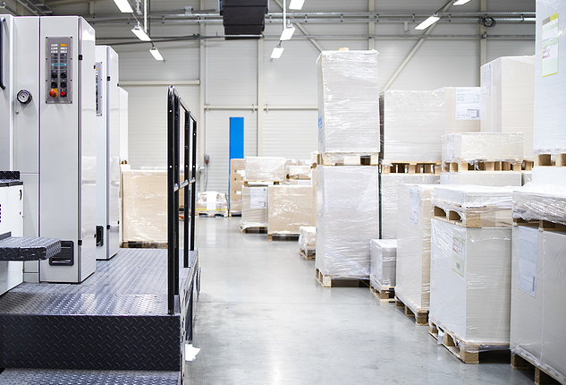 An offset press and pallets of paper in a commercial printing facility