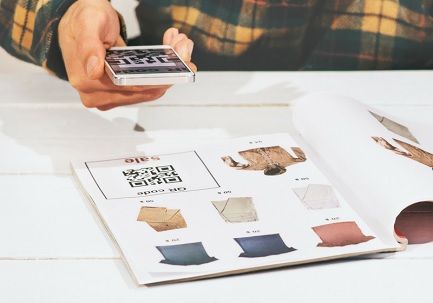 A person using a smartphone to scan a QR code printed in a clothing catalog