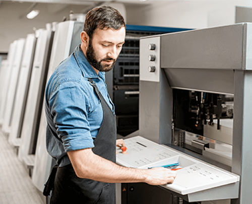 A man making adjustments to an offset printing press