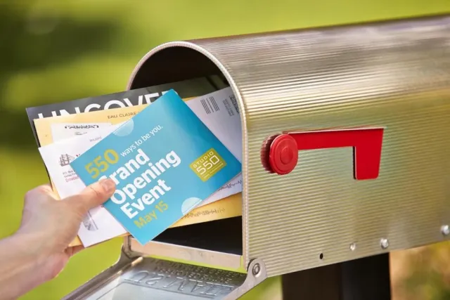 A hand removing mail from a silver mailbox