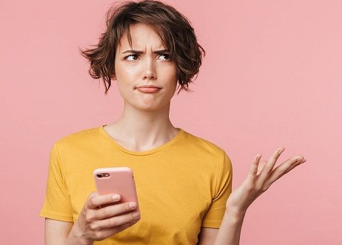 A confused woman holding a cell phone