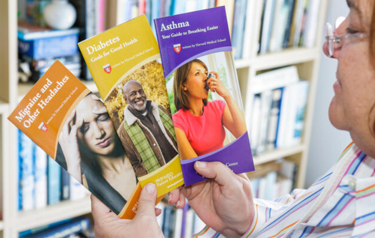 A woman holding three different medical pamphlets