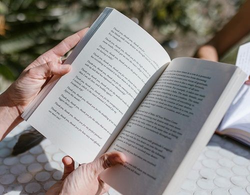 Two hands holding open a perfect bound book