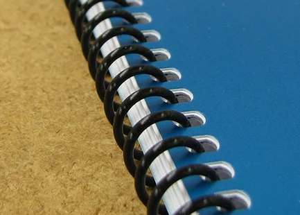 Close-up of a black spiral binding coil on a book with a blue cover