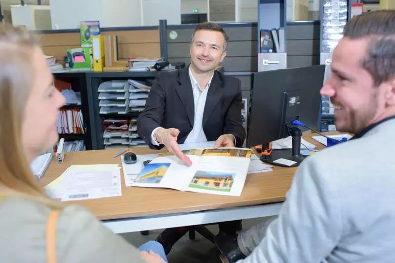 A salesman showing a brochure to a man and a woman