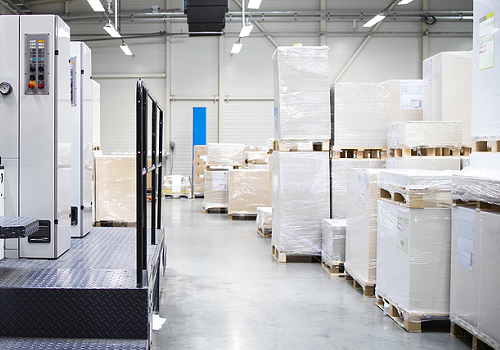 Pallets of paper next to a commercial printing press