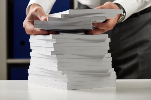 A man lifting some perfect bound books from a stack