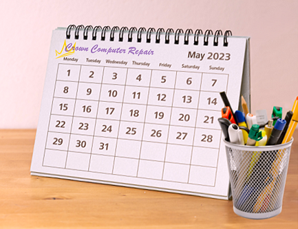 A self-standing desk calendar next to a container of pens and pencils 