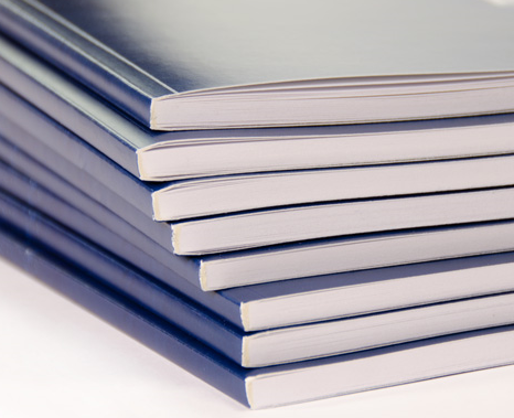 A stack of eight perfect bound books with blue covers