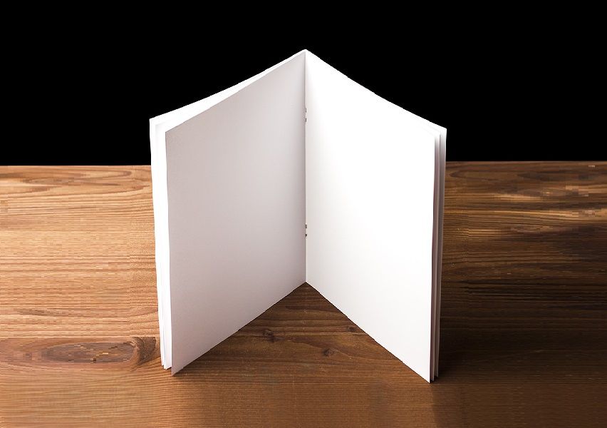 A Saddle Stitched booklet standing upright on a wooden table