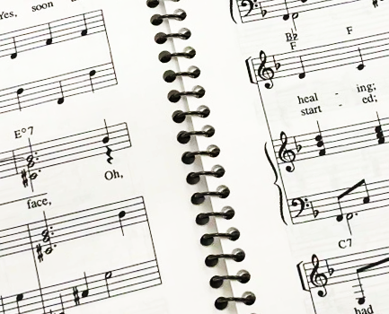 An open spiral bound book of sheet music