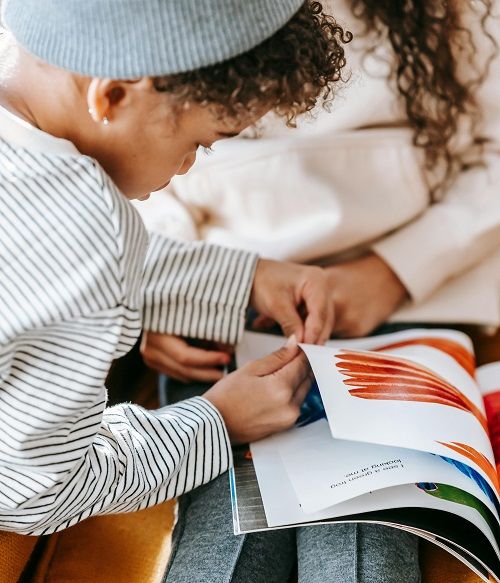 A young boy turning the pages of a softcover children's book