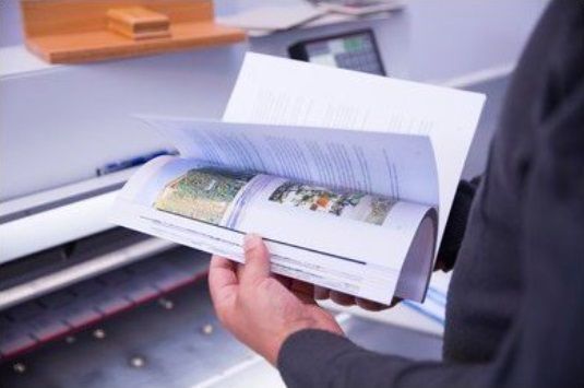 A plant worker performs a visual quality check on a perfect bound book.