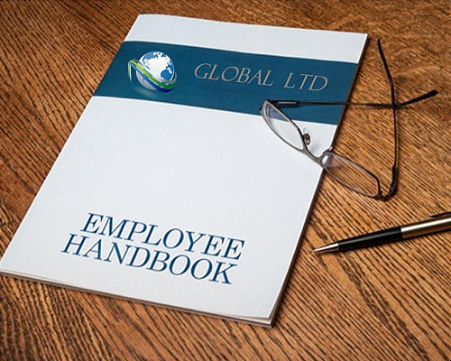 An Employee Handbook lying next to a pen and eyeglasses on a wooden tabletop 