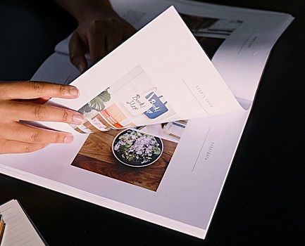 A hand turning the pages of promotional literature