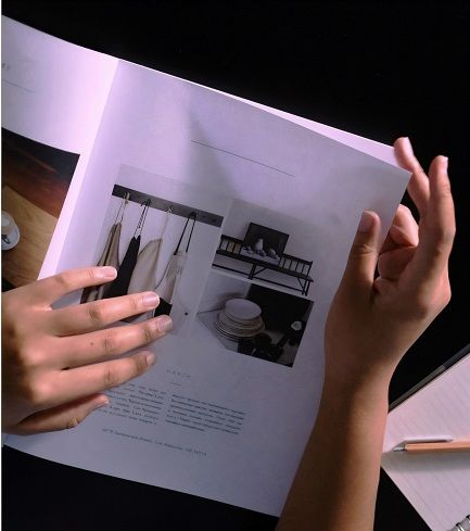Two hands turning the page of a home organization brochure