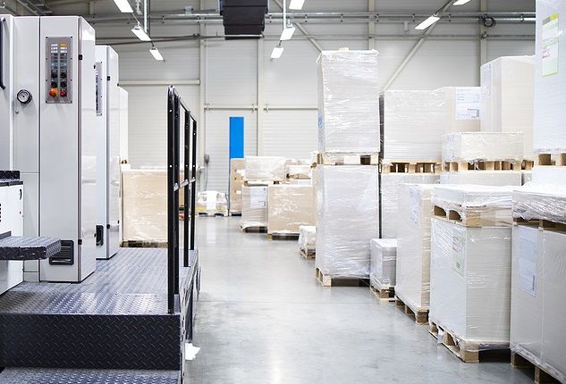 An offset press and pallets of paper in a commercial printing facility 