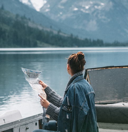 A woman reading a printed map while overlooking a mountain lake