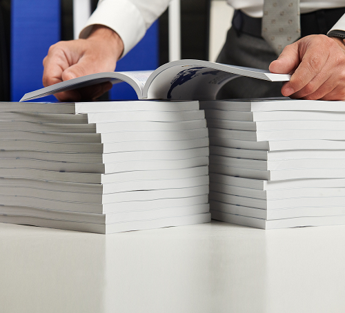 A man holding an open book above two stacks of books