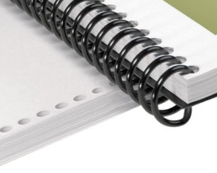 A spiral bound book lying on top of some punched pages