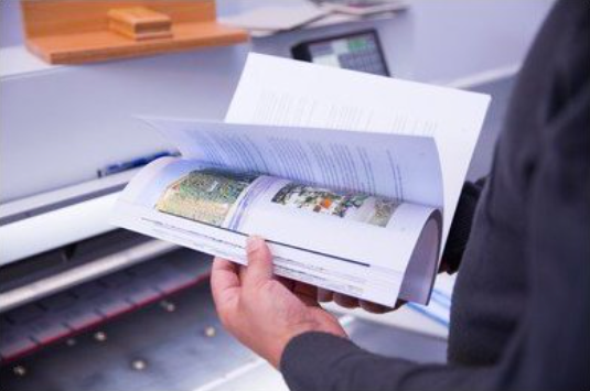 A print shop worker looking through a Perfect Bound booklding 