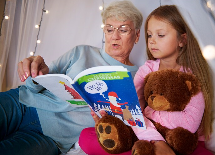 A woman reading a book to a young girl with a Teddy bear