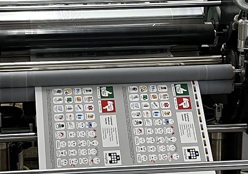 A commercial laminating machine applying a gloss laminate film to printed sheets