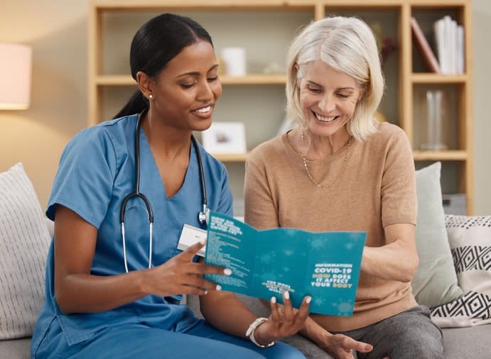 A female nurse and a female patient looking at a Covid pamphlet