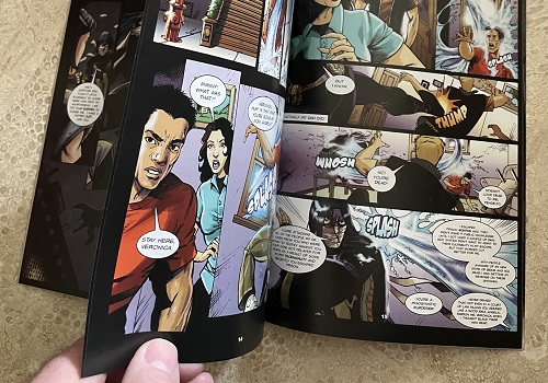 A man's hand opening the pages of an action comic book