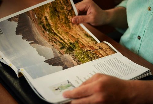 Male hands holding open a colorful travel brochure