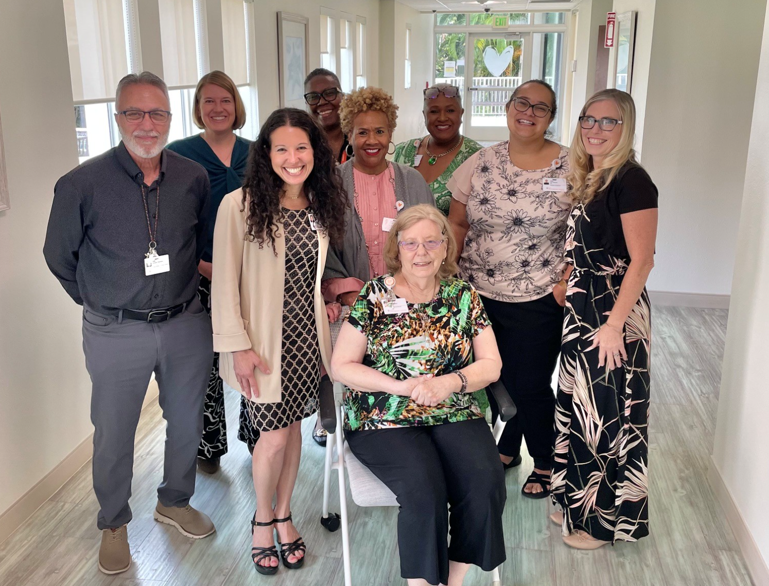 Diverse group of smiling healthcare professionals and elderly woman seated in wheelchair in bright hallway