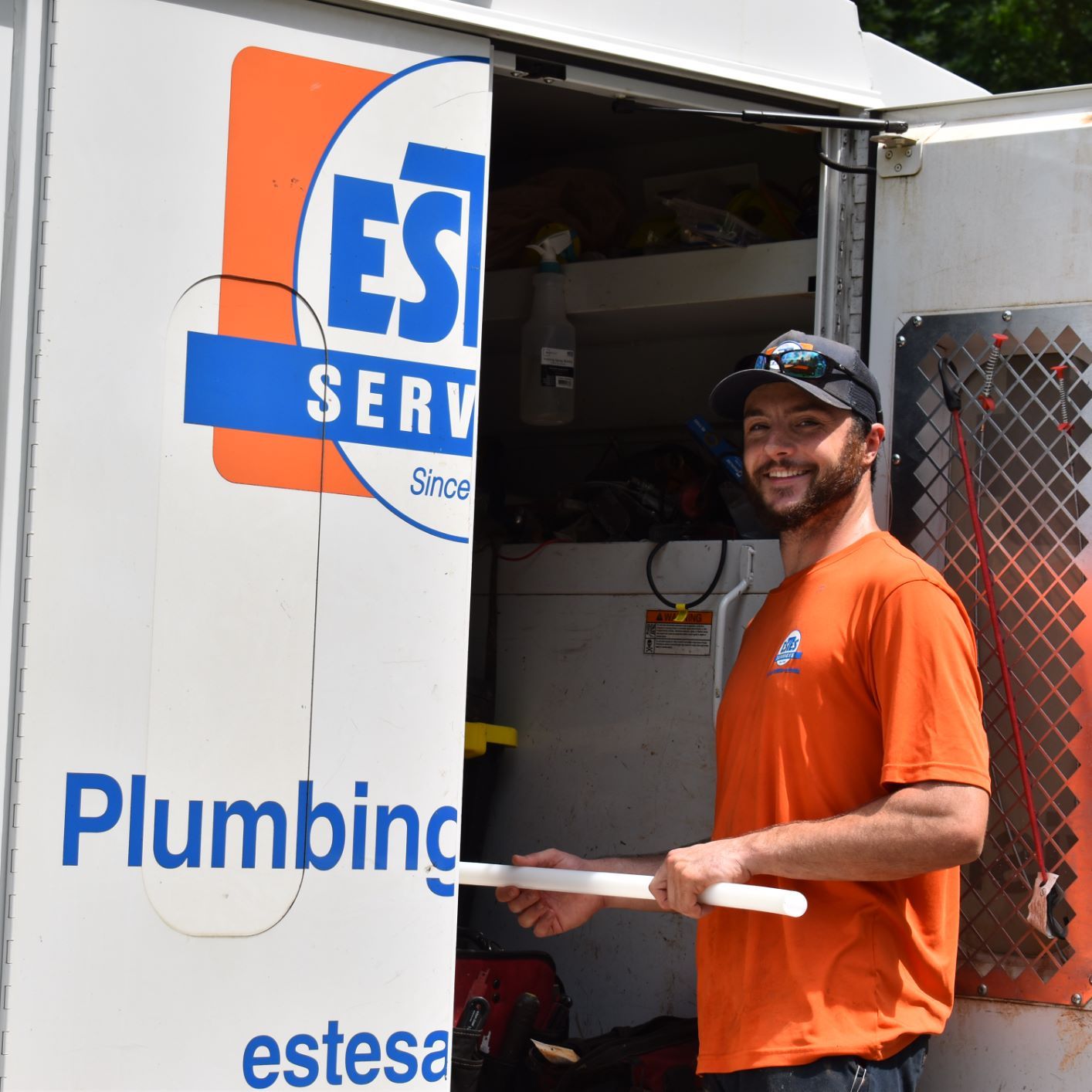 Estes Plumber smiling at the camera and holding a pipe