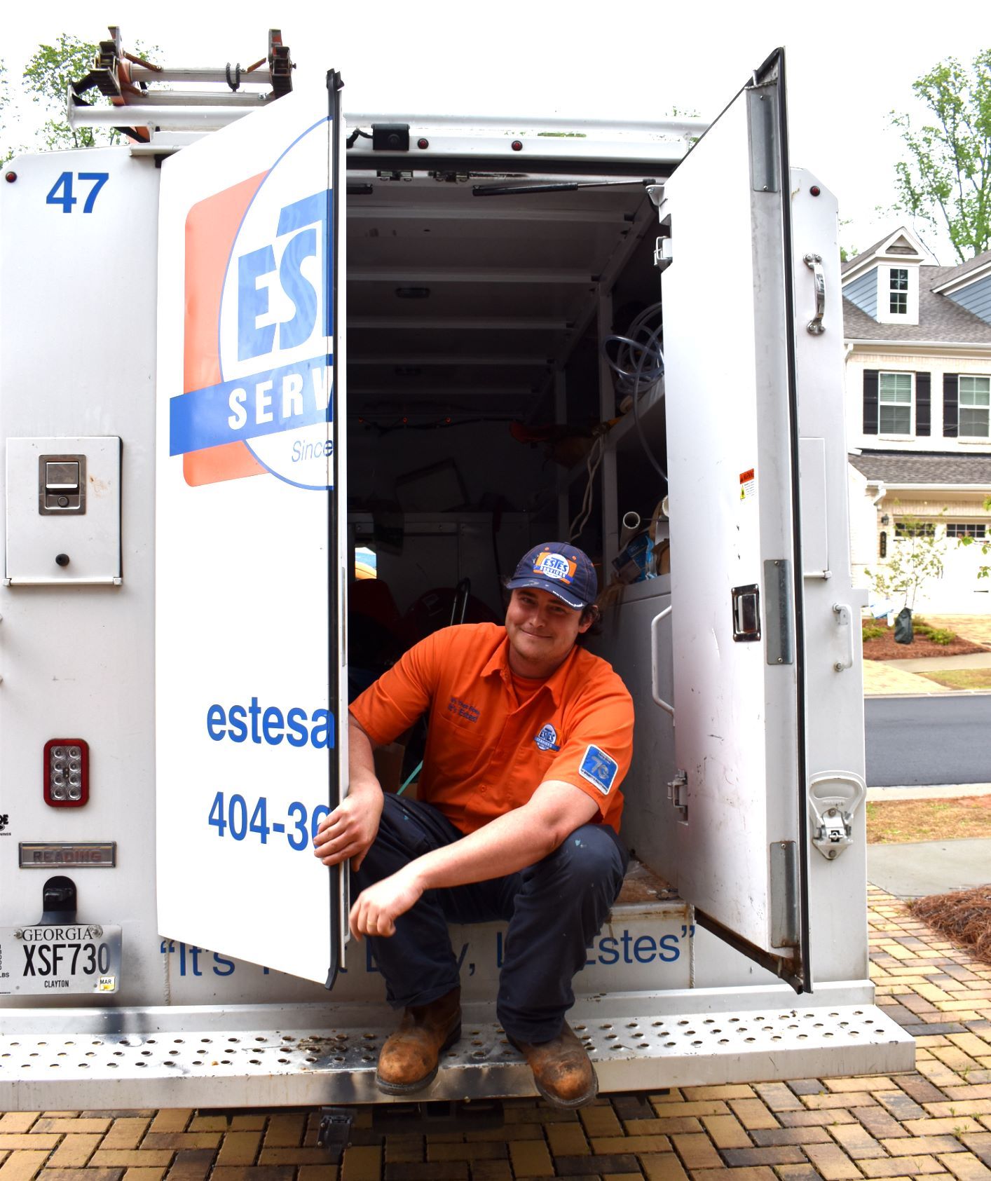 Estes Plumber sitting on an Estes truck and smiling