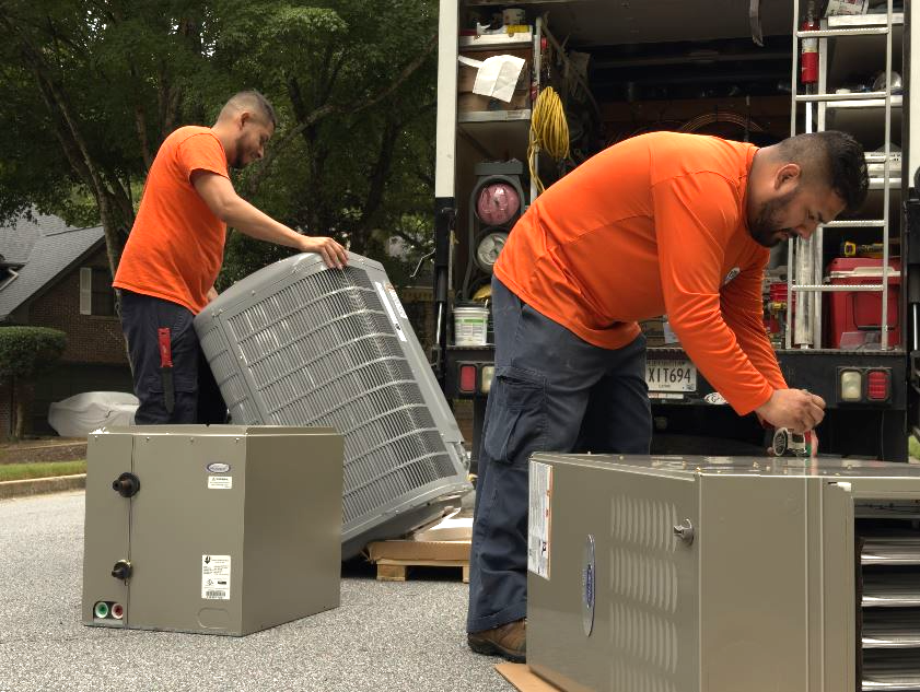 Two Estes Services Technicians preparing an HVAC equipment to install