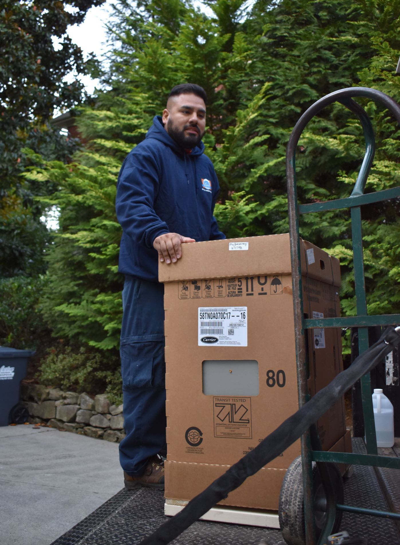 Estes Services Installer carrying a Gas Furnace for replacement