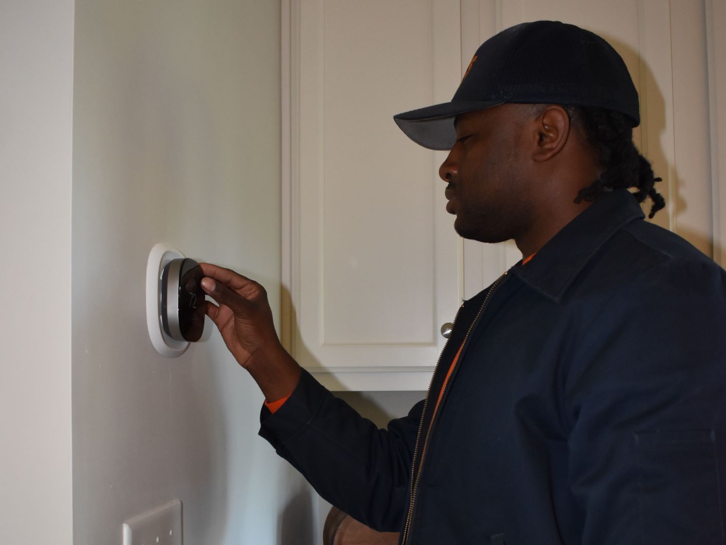 Estes Services technician adjusting a Thermostat