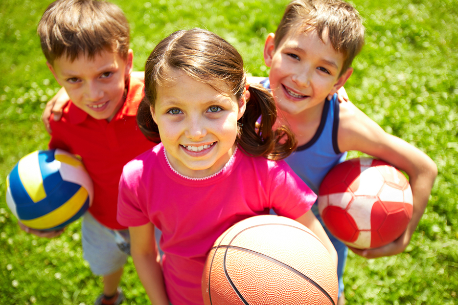 picture of three young children looking up while holding balls