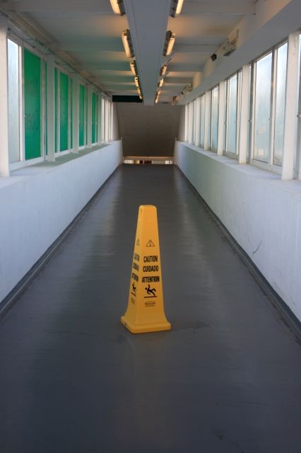 Alt text: A wet floor signage placed in the middle of a hallway.