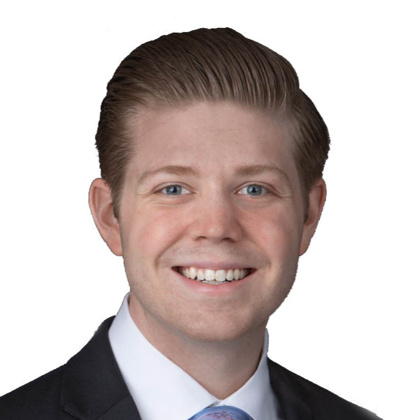 Smiling young man with neatly combed hair wearing a black suit and white shirt against a white background